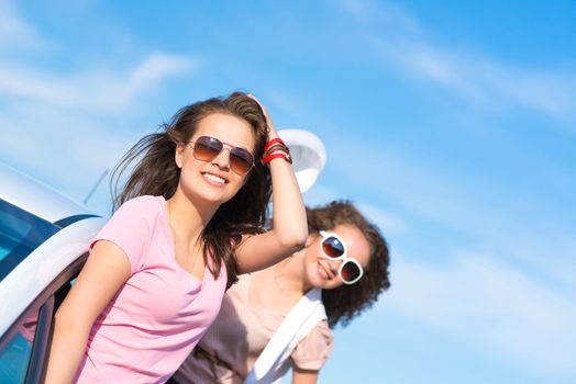 young attractive woman in sunglasses got out of the car window and laugh