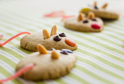 Cookies with mouse shaped and red licorice tail over green striped tablecloth