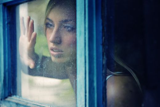 Portrait of the young lady indoors looking through the window