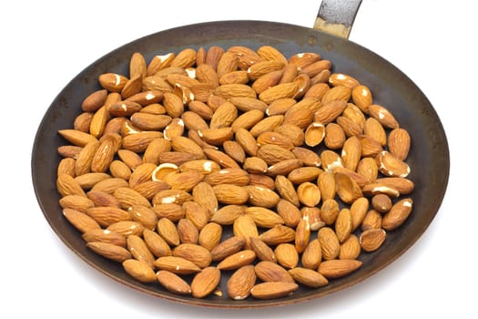 Pan with roasted almonds on white background