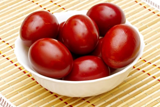 Red easter eggs in white plate on the mat