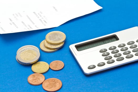 Several euro coins, bill and calculator on blue background