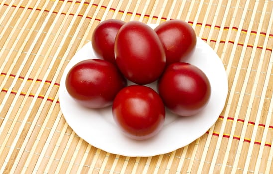 Red easter eggs in white plate on the mat
