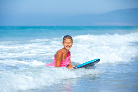 Summer vacation - Happy cute girl having fun with surfboard in the ocean