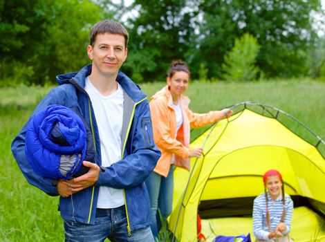 Young man camping near tent in the park