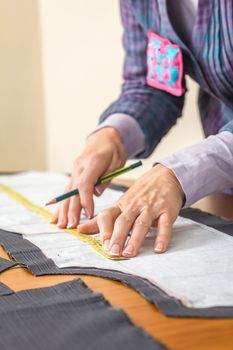 Woman dressmaker measuring tailor pattern for a suit on the table