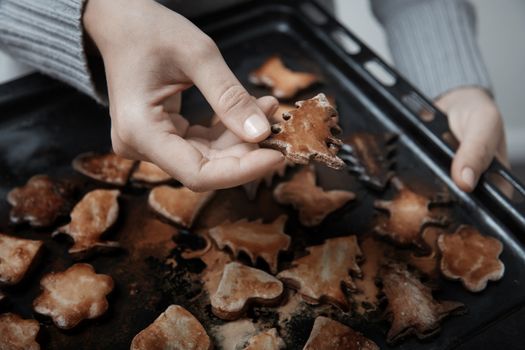 Woman holding baking tray with burnt cookies