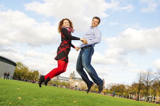 Outdoor happy couple jumping in Museumplein, Amsterdam