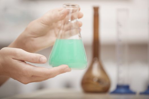 Hand of laboratory technician holding flask with chemical