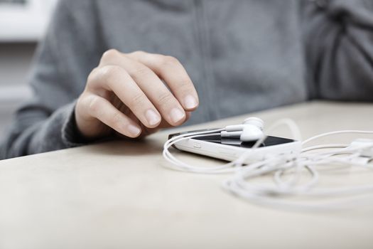 Woman hand taking smartphone with earphones