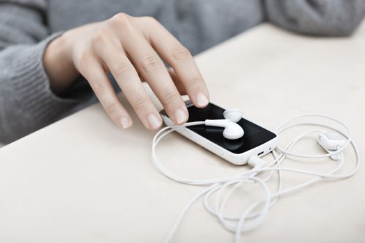 Woman hand taking smartphone with earphones