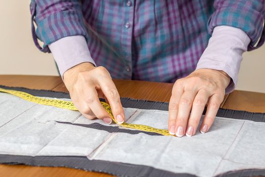 Woman dressmaker measuring tailor pattern for a suit on the table