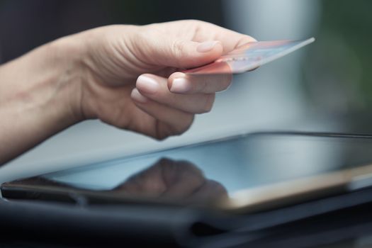 Human hand with digital tablet and credit card