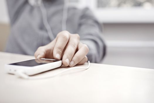 Hand of woman listening music from smartphone