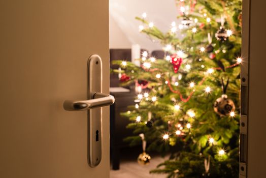 Interior shot of a modern living room with a Christmas tree as seen through the living room door