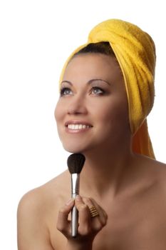 Photo of smiling model in yellow towel with cosmetic brush