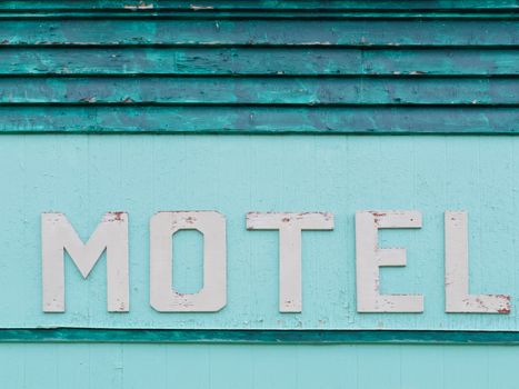 Detail of painted blue-green historic motel wooden grungy facade siding