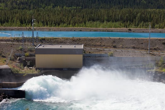 Violent torrent of white water in spillway of hydro-electric power plant with open gate at dam
