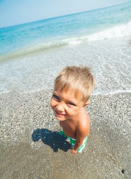 Playful boy on the beach with sea on background