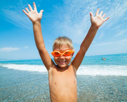 Playful boy on the beach with sea on background