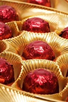 Chocolates in a red foil in a beautiful gold box