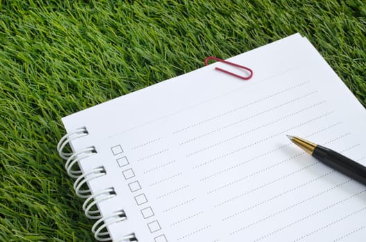 notebook and pen on artificial grass