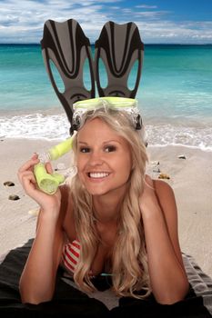 Beautiful bikini girl lying on a towel at the ocean with diving mask and flippers