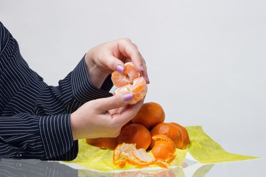 Well-groomed female hands with manicure husk tangerines