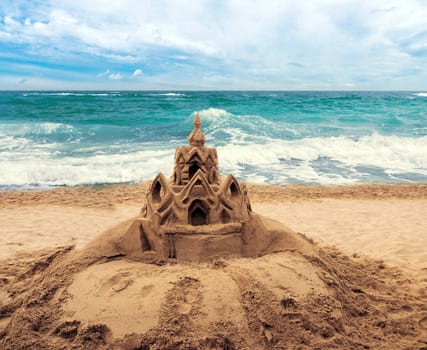 Sand castle on beach with water from wave