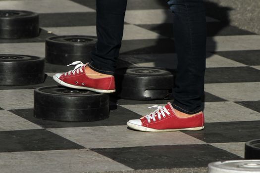 Female red shoes playing at a giant outdoor checkers