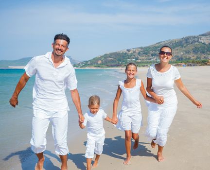 Photo of happy family running on the beach