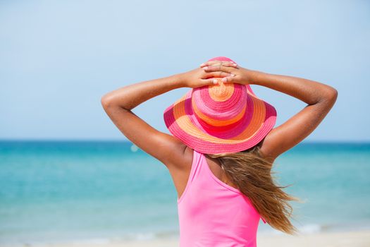 Back view of beautiful girl in pink hat and on background sea