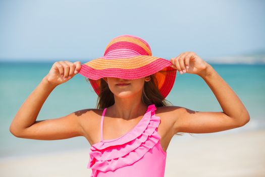 Portrait of beautiful blond girl in pink hat on background sea and blue sky