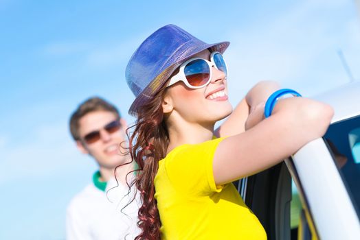 young attractive woman in sunglasses and hat stands next to a car, a close-up portrait