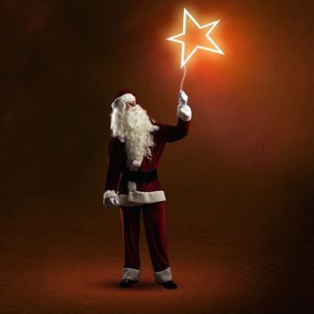 Santa Claus is holding a shining star sign on a string