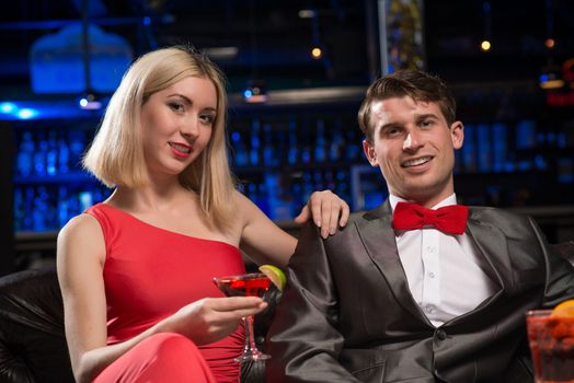 couple in a nightclub on the couch with a drink, have fun