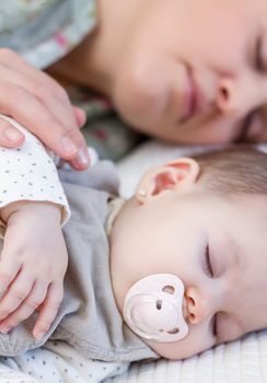 Young mother and her cute baby girl sleeping together in the bed