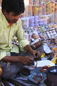 Young man fixing colorful bracelets at the market, Bundi old town, Rajasthan, India