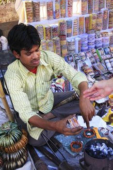 Young man fixing colorful bracelets at the market, Bundi old town, Rajasthan, India