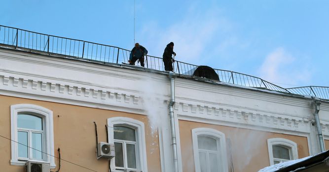 Workers clean snow from the roof