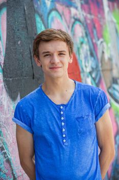 Portrait of happy teens boy having fun near painted wall