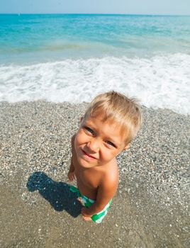 Playful boy on the beach with sea on background
