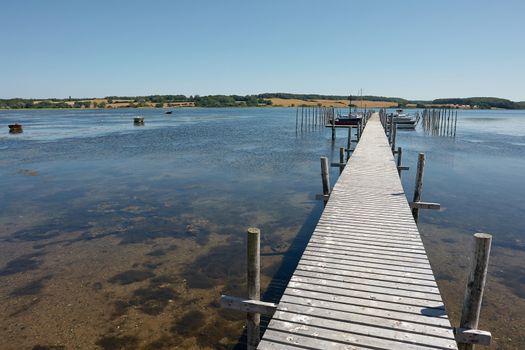 Beautiful seascape of a wooden footbridge in a marina with small boats                               