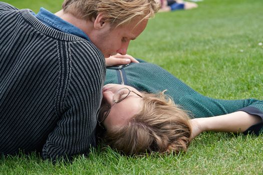 Young couple deeply in love outdoors on the grass in a park