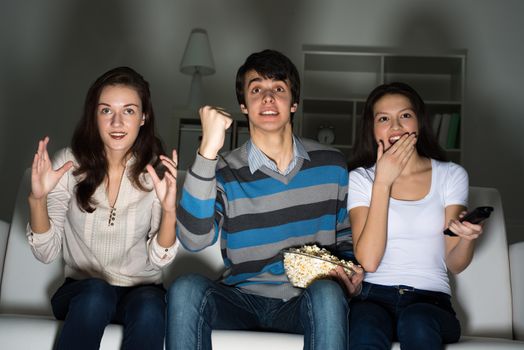 group of young people watching TV on the couch, sports fans