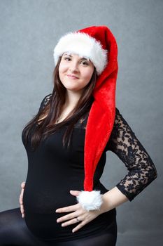 beautiful smiling pregnant young santa woman tenderly holding her tummy