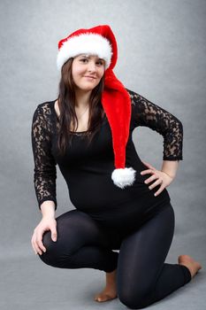 beautiful smiling pregnant young santa woman tenderly holding her tummy