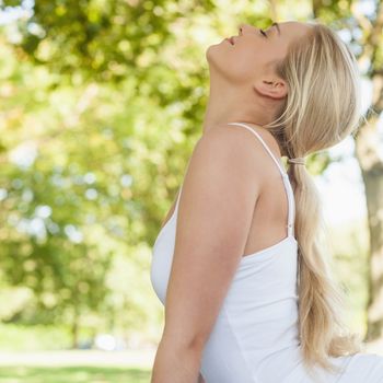 Profile view of blonde young woman doing yoga in a park with closed eyes