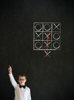 Hand up answer boy dressed up as business man with thinking out of the box tic tac toe concept on blackboard background