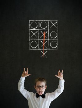 Knowledge rocks boy dressed up as business man with thinking out of the box tic tac toe concept on blackboard background